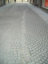 A memorial has been created on the street.  The faint curvy line is a gold color and commerates those that defied the Nazis by dodging the requirement to salute the plaque.