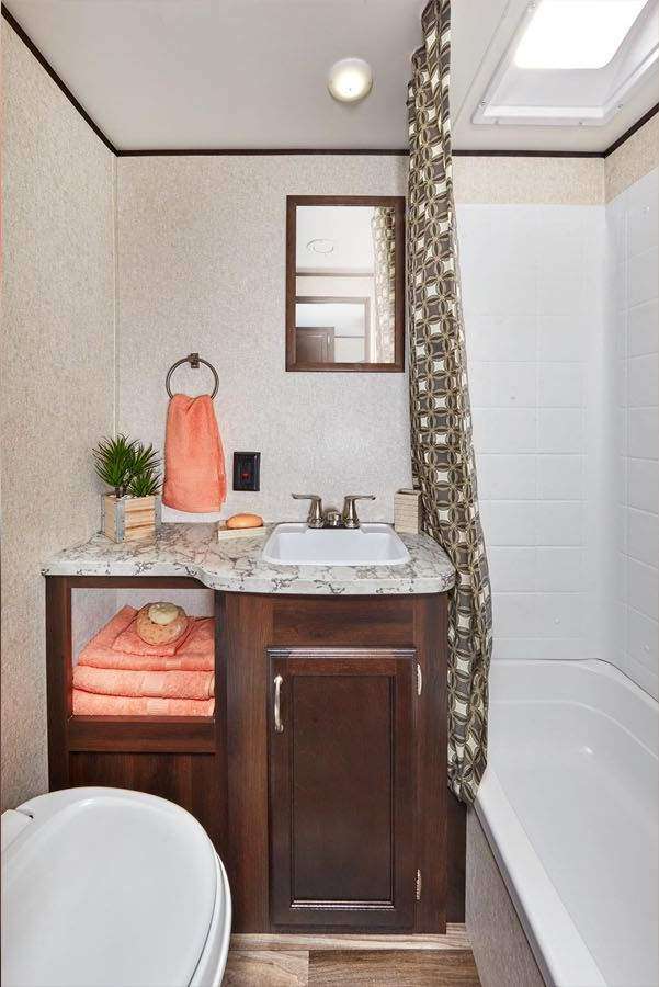 There is plenty of room in the bathroom.  When sitting on the toilet, your knees will not hit a wall or the door.  Also, the shower is plenty tall for a 6 foot plus person as the skylight over the tub extends up above the roof line.
