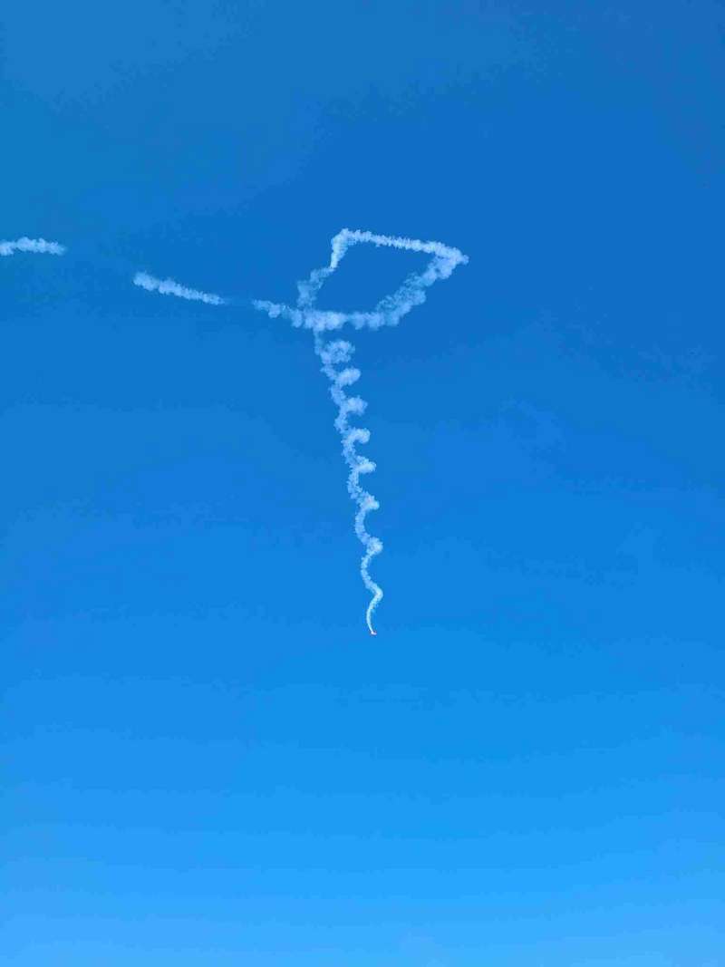 A biwing plane making corkscrews in the sky