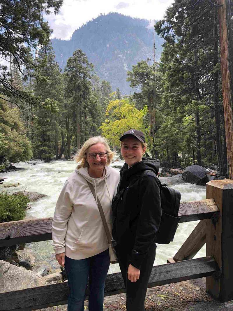 Susanne and Frederike standing on a bridge crossing the Merced River in Yosemite National Park. Notice how high the river is.  A couple of months earlier, it flooded the park.