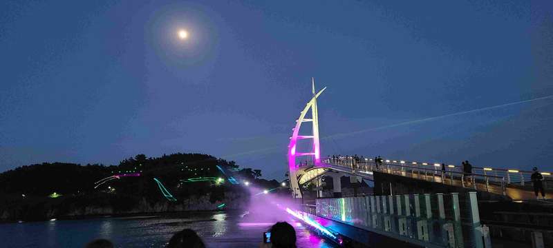 The laser beams are shot across the water and draw images on the island.
