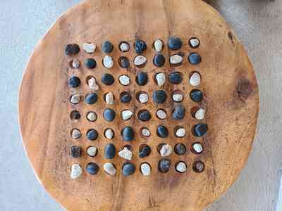 A traditional Kōnane stone board arranged with black lava and white coral pieces.