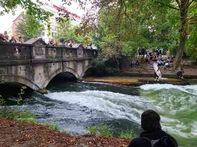 The Isar river is flowing under the bridge in such a manner as to create a standing wave.